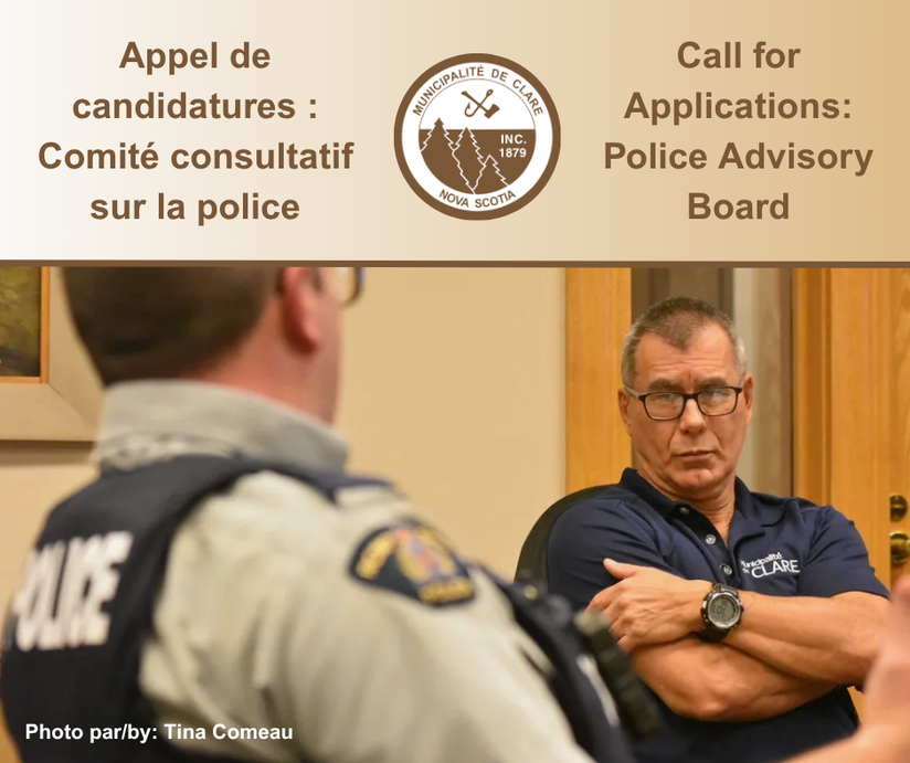 A picture snapped from behind an RCMP officer sitting at a table speaking to Councillor Carl Deveau